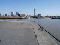 a bike leaning against an outdoor bench by a body of water with city buildings in the background