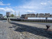 a black iron structure sitting on the curb next to water and a building with windows