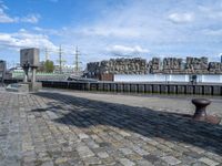 a black iron structure sitting on the curb next to water and a building with windows