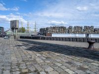 a black iron structure sitting on the curb next to water and a building with windows