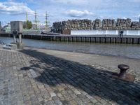 a black iron structure sitting on the curb next to water and a building with windows