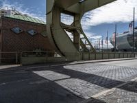 the view looking up from inside an arch at the docks with ships behind it and buildings and the bridge over it