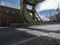 the view looking up from inside an arch at the docks with ships behind it and buildings and the bridge over it