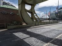 the view looking up from inside an arch at the docks with ships behind it and buildings and the bridge over it