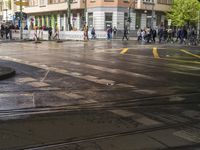 the people are waiting in the wet tracks of an empty street in town during the rain