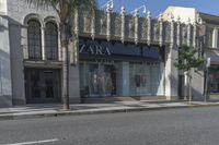 two people walking down a street past stores with palm trees in front of them's windows