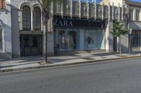 two people walking down a street past stores with palm trees in front of them's windows