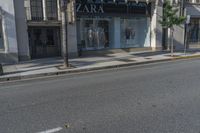 two people walking down a street past stores with palm trees in front of them's windows