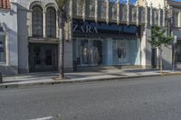 two people walking down a street past stores with palm trees in front of them's windows