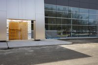 the entrance to a building with a door on it's side by the building with a large window