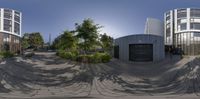 a fish eye view of a road in front of some buildings with green plants on the side