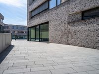 a brick and glass walkway near building windows on a sunny day in a city with no one going