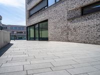 a brick and glass walkway near building windows on a sunny day in a city with no one going