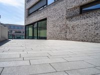 a brick and glass walkway near building windows on a sunny day in a city with no one going