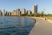 a view of buildings and water, including a few people walking along it near the shore