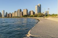 a view of buildings and water, including a few people walking along it near the shore