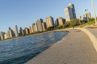 a view of buildings and water, including a few people walking along it near the shore