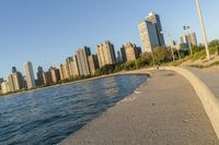 a view of buildings and water, including a few people walking along it near the shore