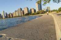 a view of buildings and water, including a few people walking along it near the shore