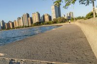 a view of buildings and water, including a few people walking along it near the shore