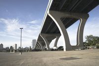 the sidewalk in a parking lot next to a bridge over water and some tall buildings