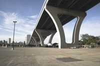 the sidewalk in a parking lot next to a bridge over water and some tall buildings