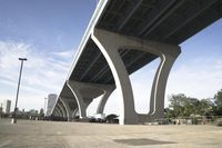 the sidewalk in a parking lot next to a bridge over water and some tall buildings