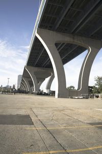 the sidewalk in a parking lot next to a bridge over water and some tall buildings