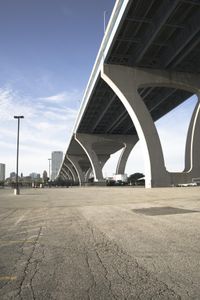 the sidewalk in a parking lot next to a bridge over water and some tall buildings