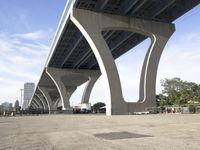 the sidewalk in a parking lot next to a bridge over water and some tall buildings