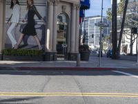 people are walking down the road near a store with blue and white awnings