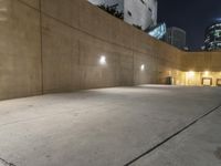 the empty parking lot in front of the building is lit up at night time with lights on all around