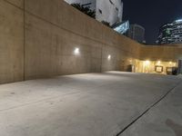 the empty parking lot in front of the building is lit up at night time with lights on all around