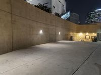 the empty parking lot in front of the building is lit up at night time with lights on all around