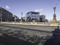 a building with a large sculpture on the street with snowy ground below it and buildings behind it