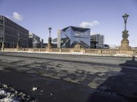 a building with a large sculpture on the street with snowy ground below it and buildings behind it