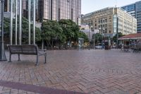 a bench sitting in a plaza next to some large buildings on a street corner,