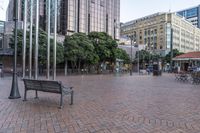 a bench sitting in a plaza next to some large buildings on a street corner,