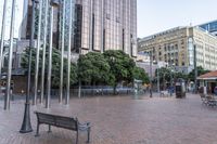 a bench sitting in a plaza next to some large buildings on a street corner,