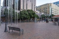 a bench sitting in a plaza next to some large buildings on a street corner,