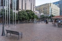 a bench sitting in a plaza next to some large buildings on a street corner,