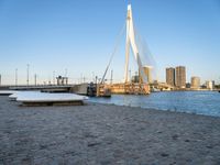 the large bridge in front of the water is crossing over the snow covered shore, in the city