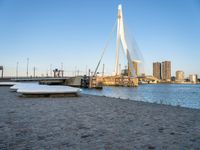 the large bridge in front of the water is crossing over the snow covered shore, in the city