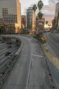 the freeway is wide and wide with tall buildings in it, near the street, trees and palm trees