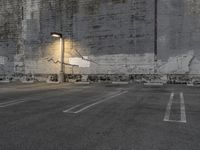 a concrete parking lot with a building in the back ground and street lights on top of it
