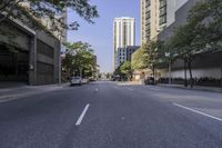 an empty street lined with tall buildings in a city area next to trees and trees