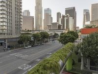 a view of an empty city from a skyscraper block across a street with parked cars