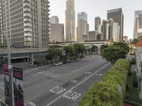 a view of an empty city from a skyscraper block across a street with parked cars