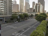 a view of an empty city from a skyscraper block across a street with parked cars