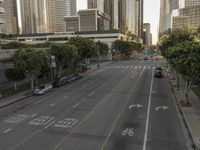 a view of an empty city from a skyscraper block across a street with parked cars